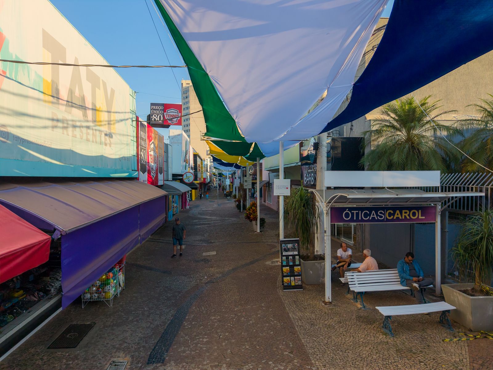 Velas de tecido azul, verde e amarelo cobrindo a rua, vistas de baixo